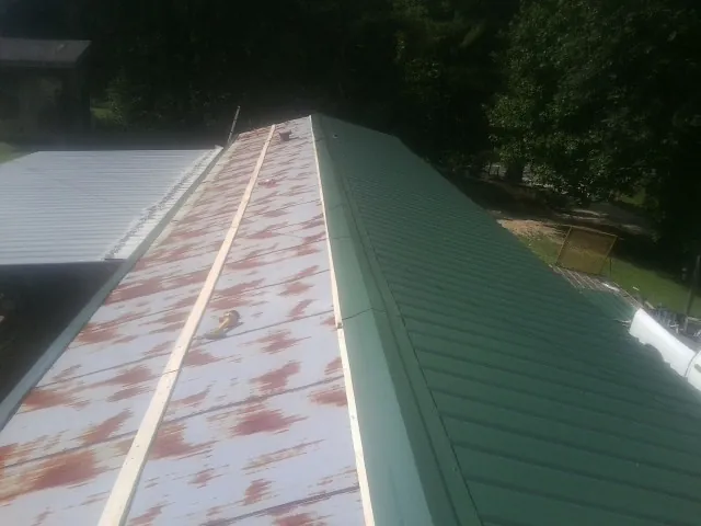 Old rusted panels beside newly installed green metal roofing — Wind Damage Roof Repair by Roofing Brothers in Yorkshire