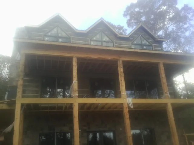 Dormers and porch framing on a large log home under construction — Roof Coating work by our crew in Yorkshire