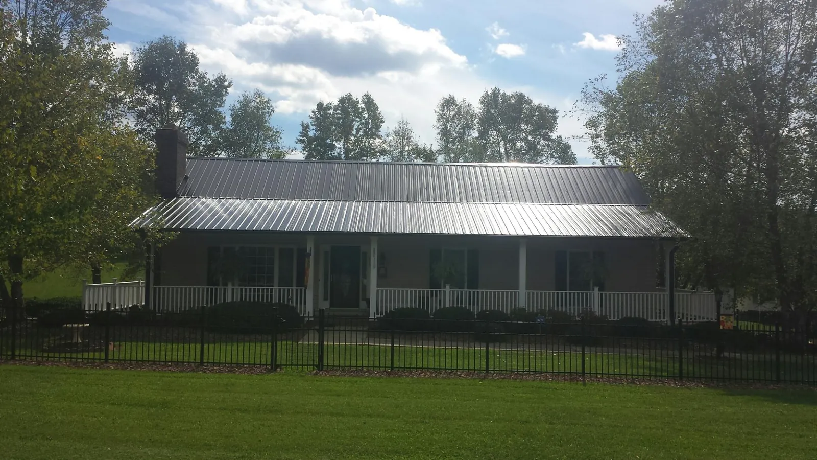 Gray metal roof on a brick ranch with a full width front porch — Gutter Guard Installation work by our crew in Yorkshire