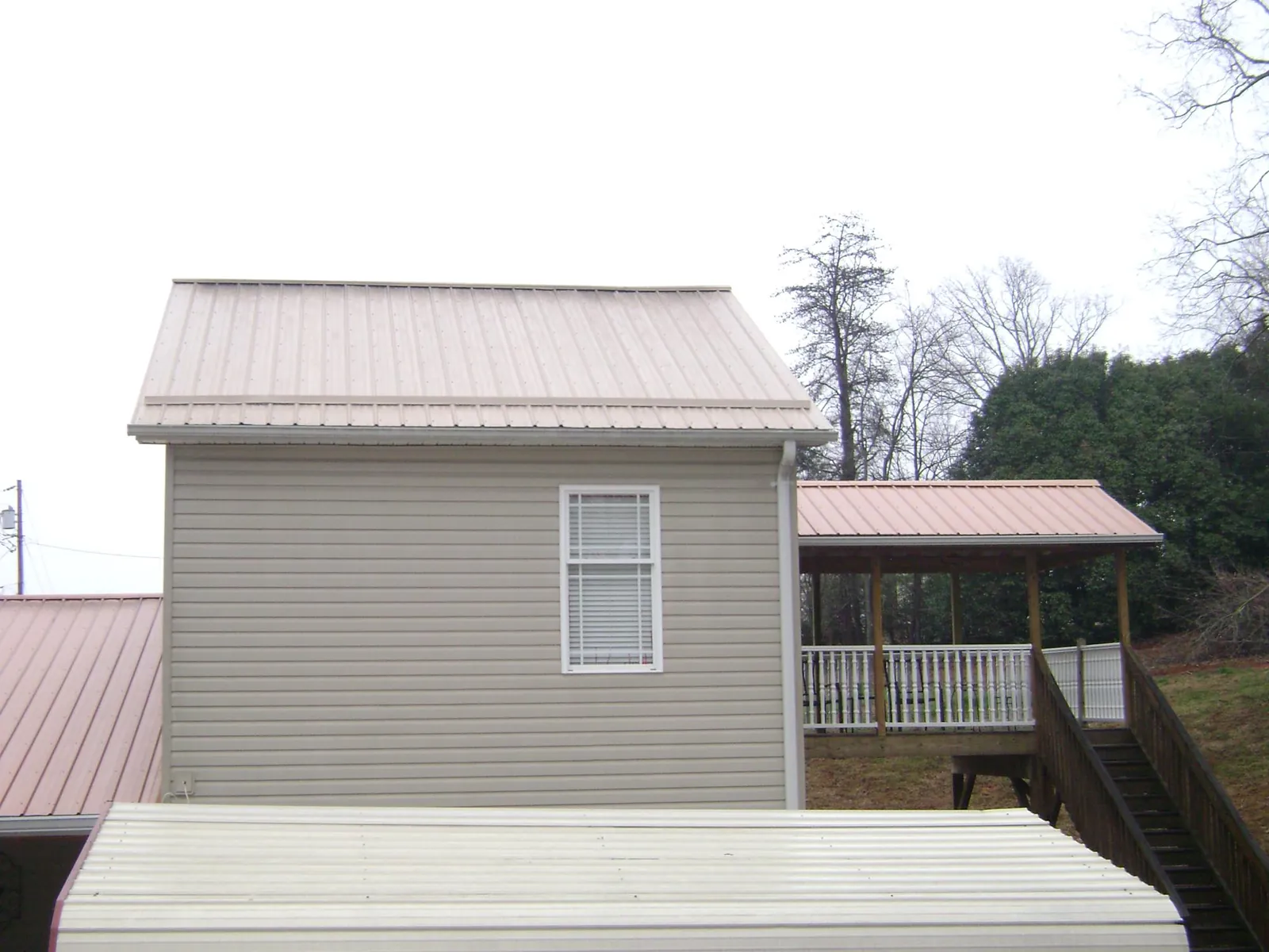 Tan metal roofs on a two story addition and attached porch, from a Roof Replacement job in Yorkshire
