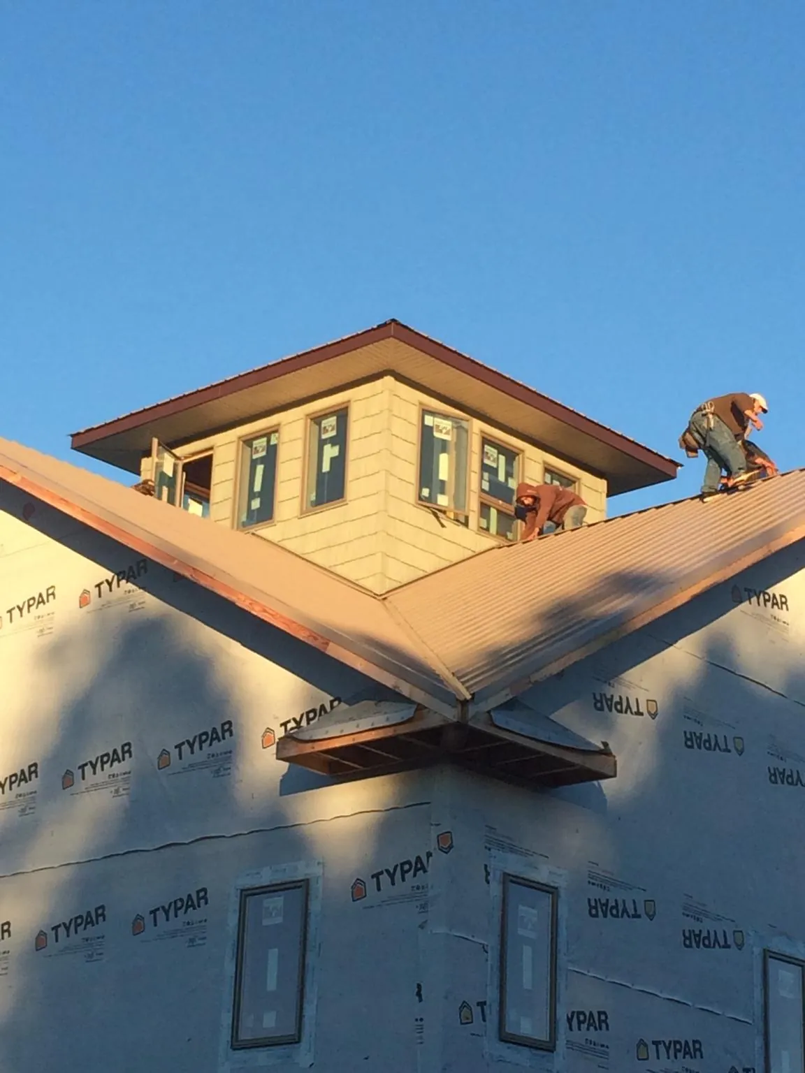Roofers working around a rooftop cupola on a new metal roof at sunset — Roof Waterproofing in Yorkshire by Roofing Brothers